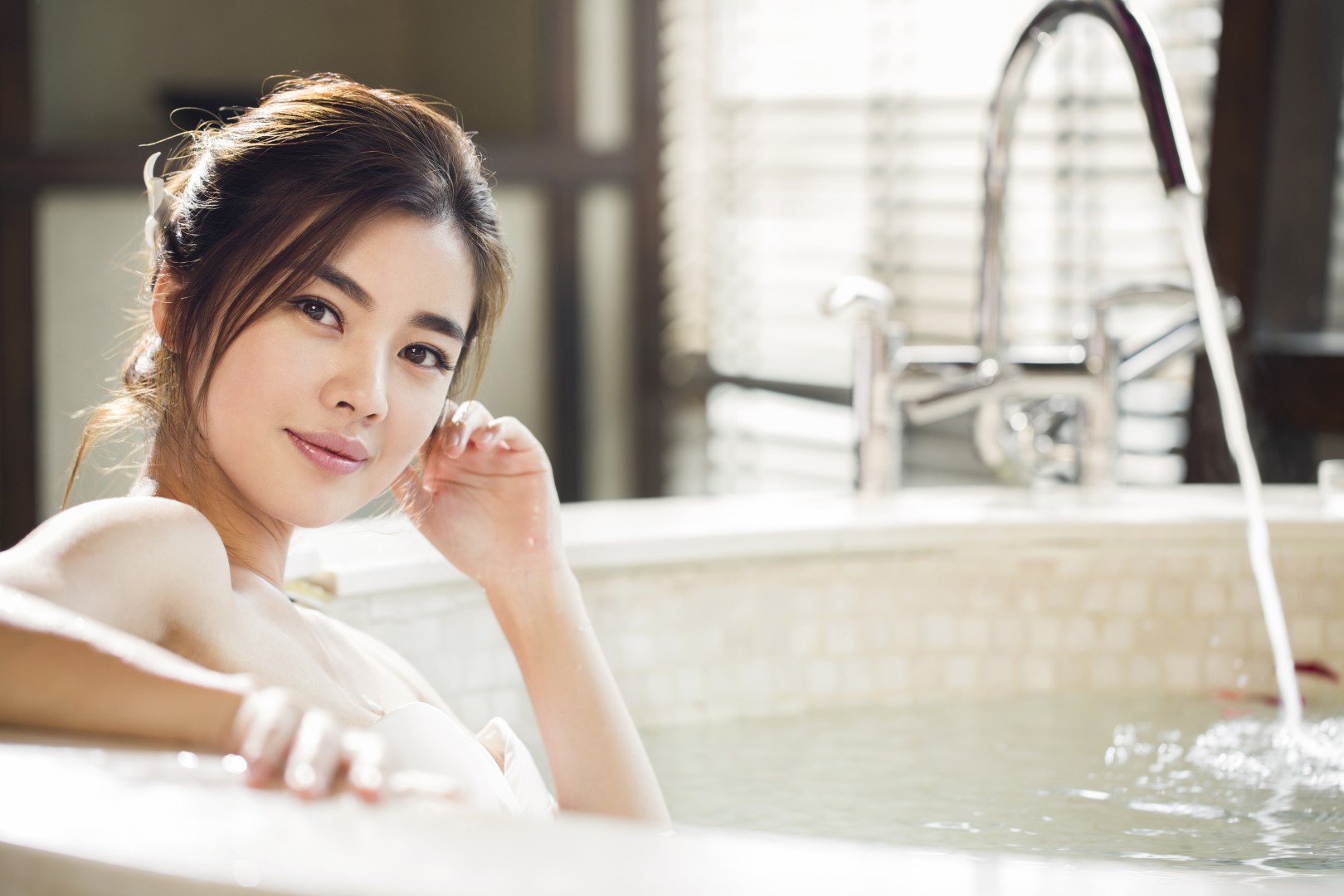 Beautiful young Chinese woman in bathtub with rose petals